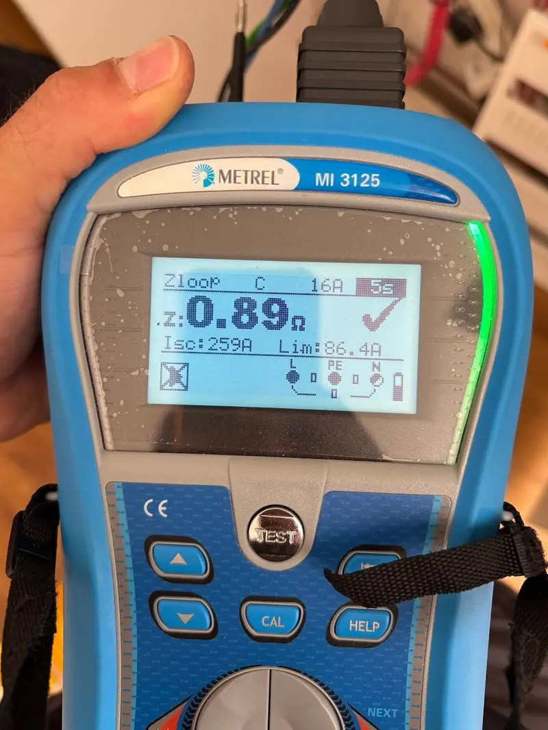 מכשיר בדיקה Metrel, ועל המסך תוצאת מדידה של 0.89 אוהם